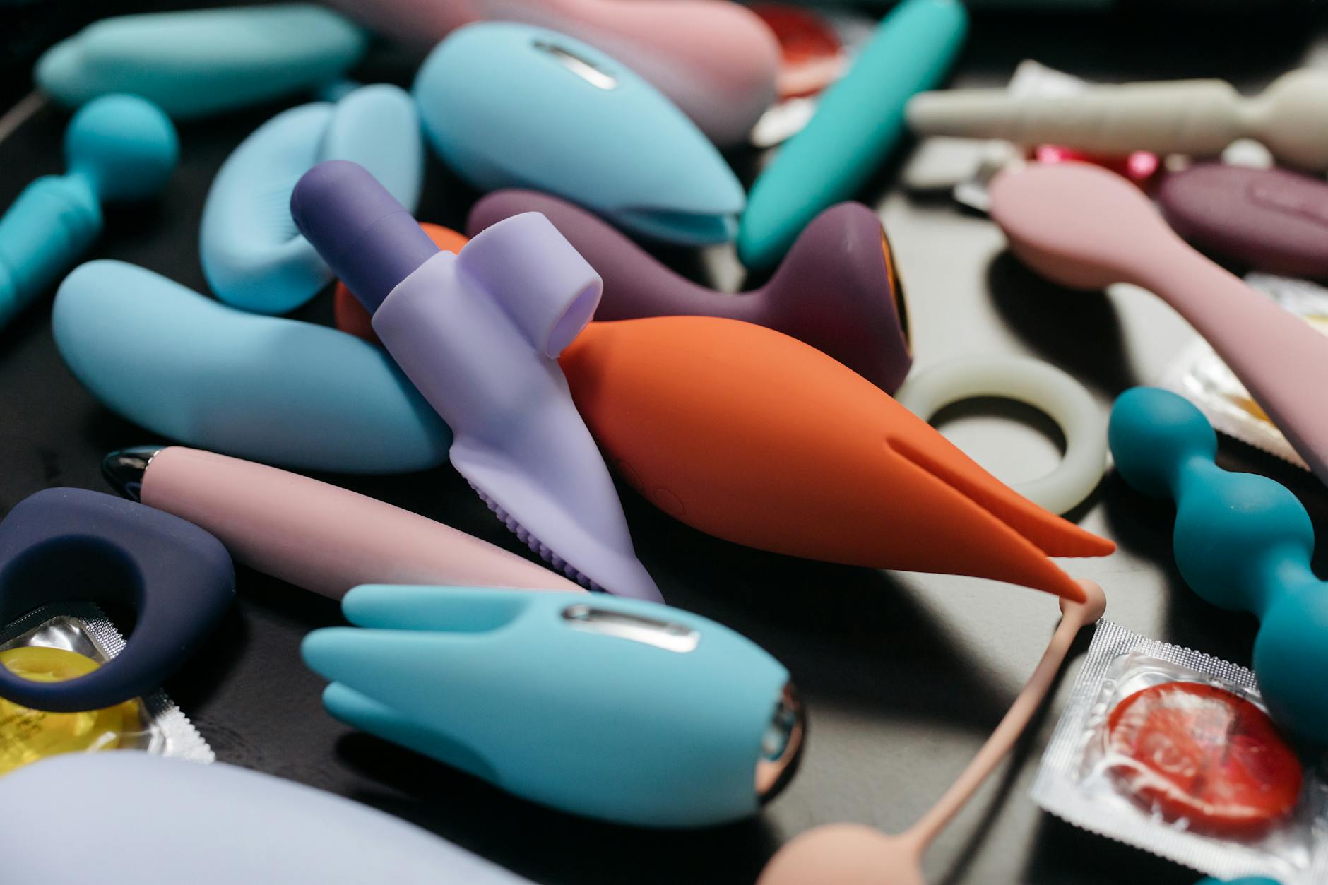Hand hält einen orangefarbenen Vibrator vor minimalistischem violettem Hintergrund