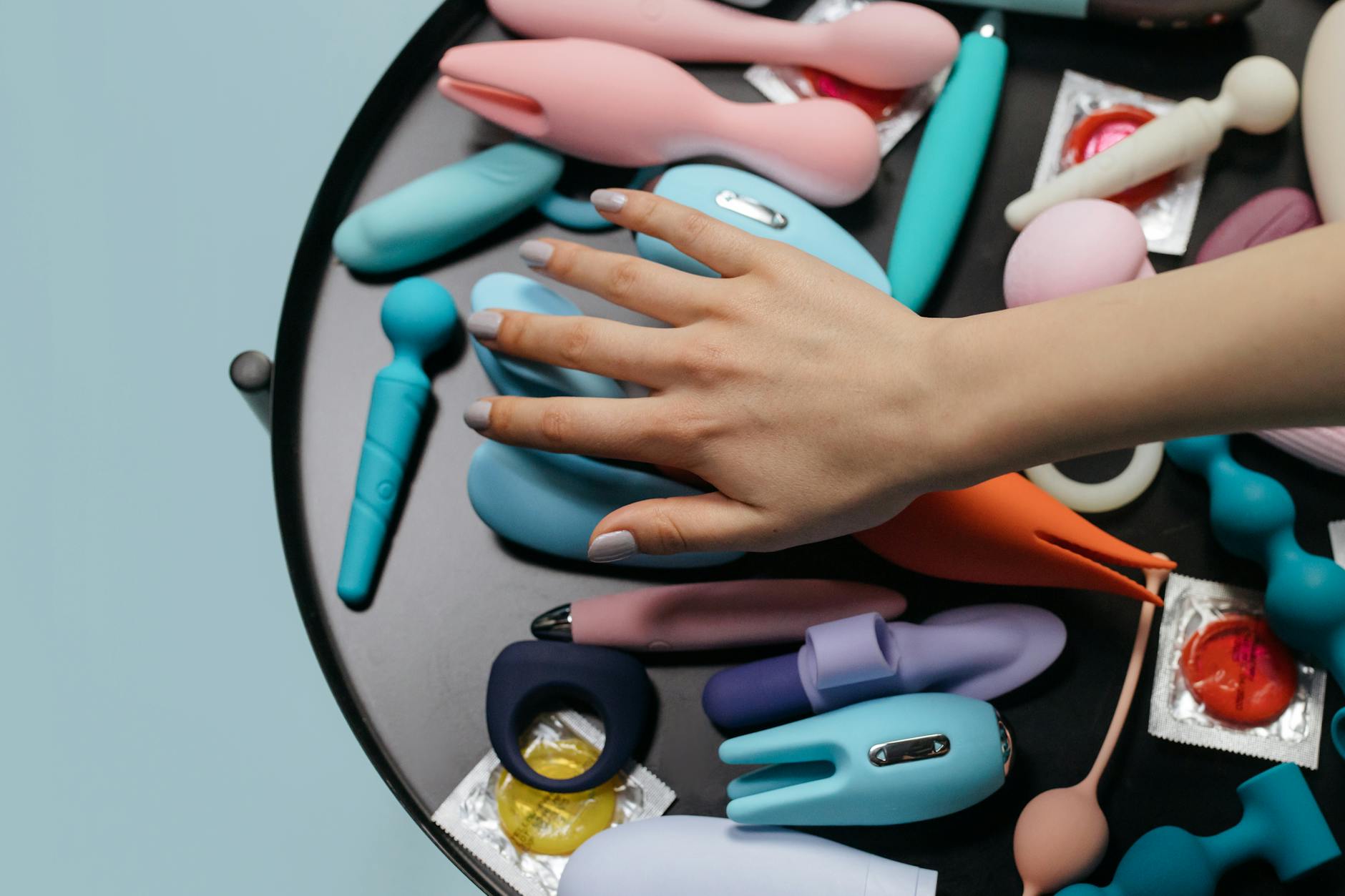 Eine blaue Silikonvibrator in der Hand vor violettem Hintergrund, Selbstliebe und Sexualität fördernd