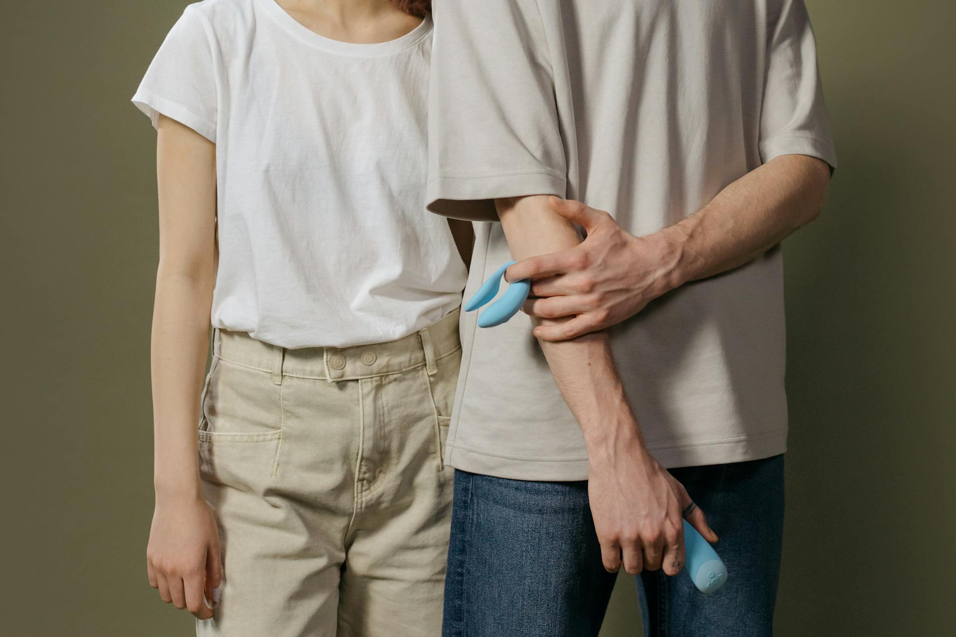 Frau mit Brille hält blaue und rosa Silikon-Vibratoren in nachdenklicher Pose